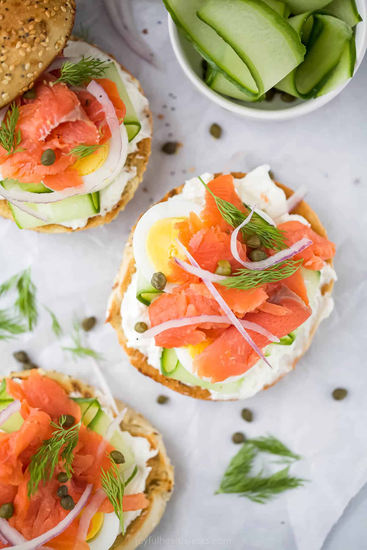 Topped with cream cheese, this bagel and lox recipe is the perfect 5-minute breakfast. It's crunchy, savory, spicy, and packed with veggies! Three open bagels and lox with toppings and capers.