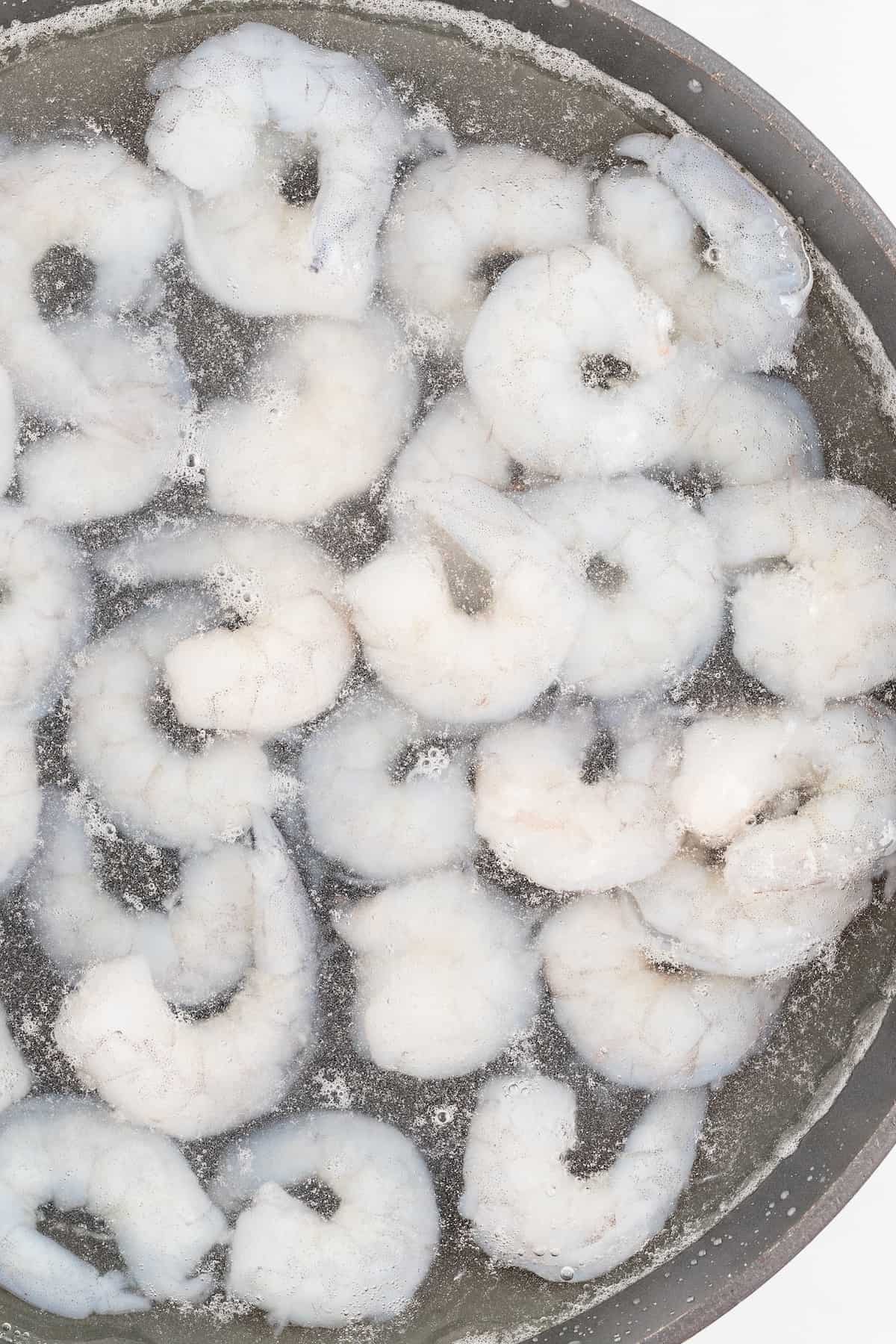 Adding the raw shrimp to the pot of water. 