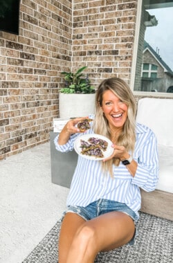 girl sitting on the floor holding daily harvest flatbread and smiling