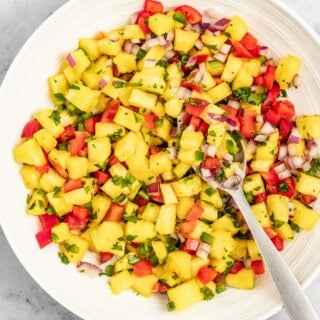 Bowl of pineapple salsa with a metal spoon.