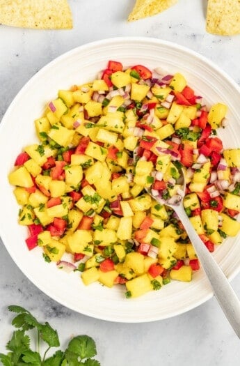 Bowl of pineapple salsa with a metal spoon.