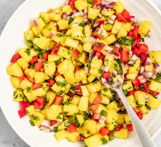 Bowl of pineapple salsa with a metal spoon.
