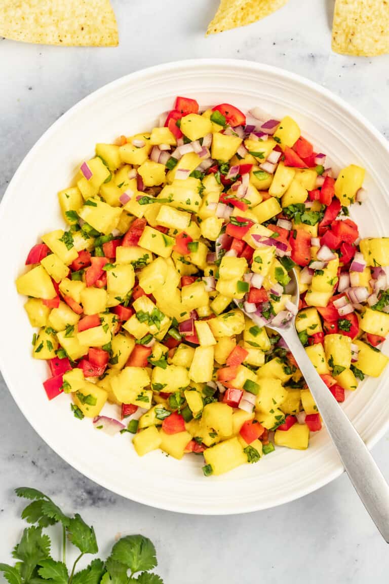 Bowl of pineapple salsa with a metal spoon.