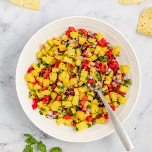 Pineapple salsa in a bowl with corn chips on the side.