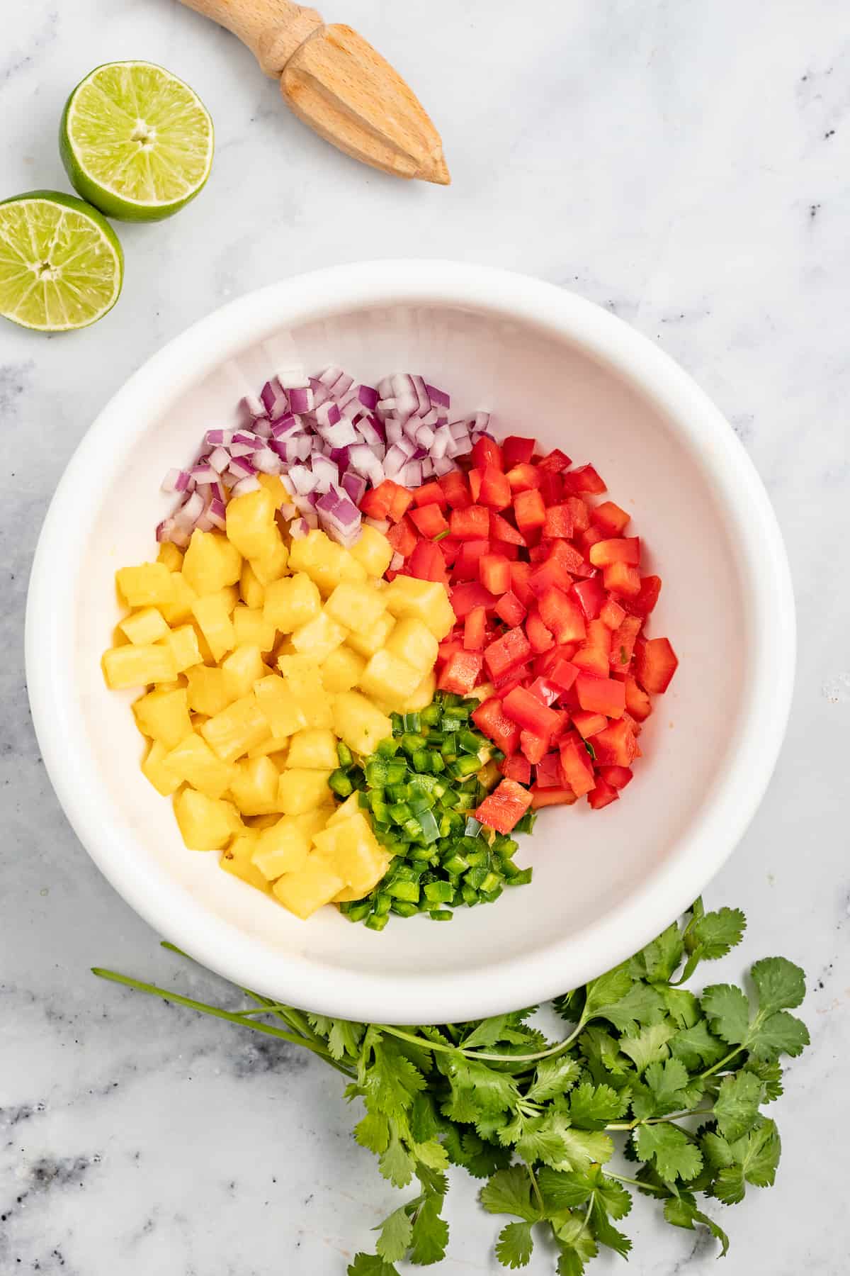 With bell pepper and jalapeño, this 15-minute pineapple salsa is a tangy, fruity, and crunchy addition to your all your meals. Adding the salsa ingredients to the bowl.