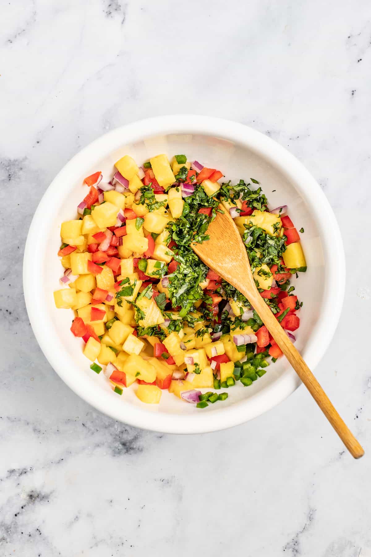 With bell pepper and jalapeño, this 15-minute pineapple salsa is a tangy, fruity, and crunchy addition to your all your meals. Mixing the salsa ingredients in the bowl.