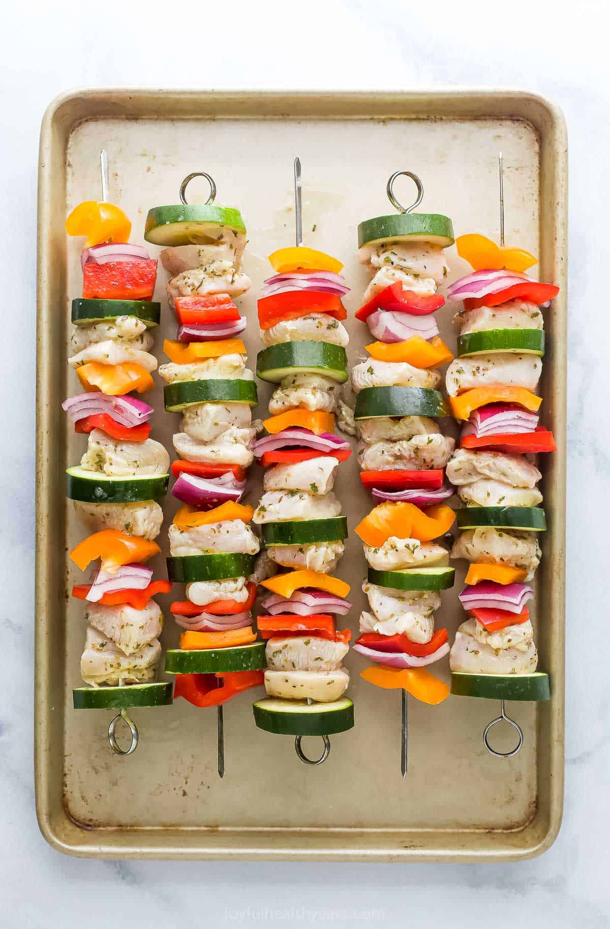 Uncooked skewers on a baking sheet. 