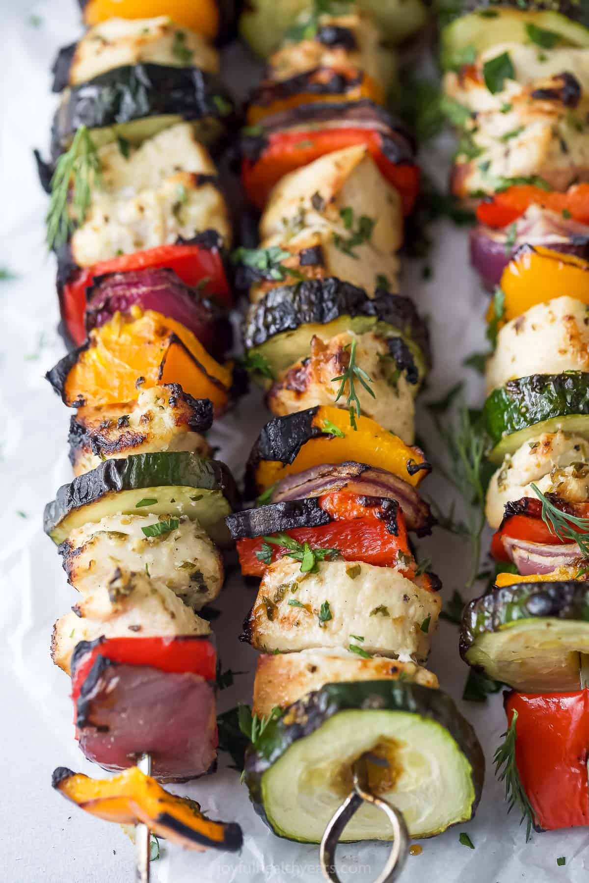 Close-up of charred veggies and chicken on the Mediterranean chicken kabobs. 