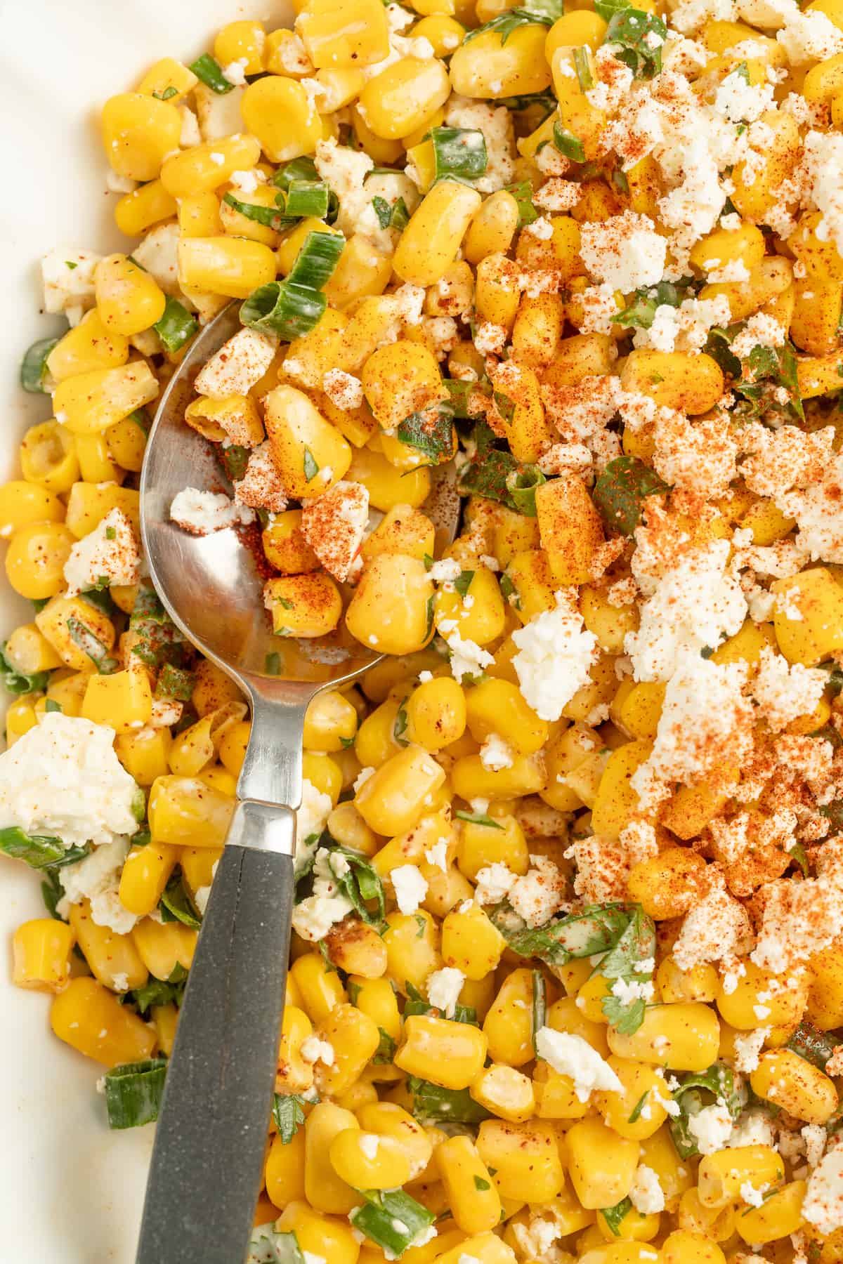 Close-up of Mexican street corn dip with a metal spoon.