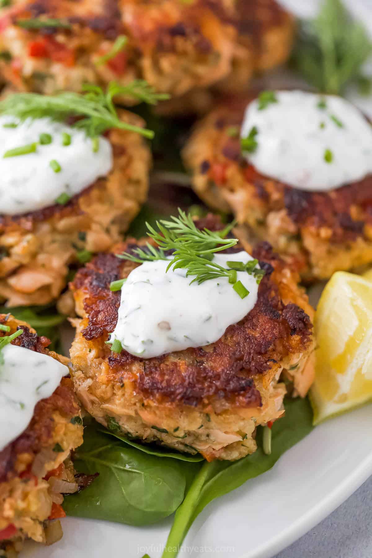 Close-up of salmon cakes with a dollop of lemon dill sauce on top.