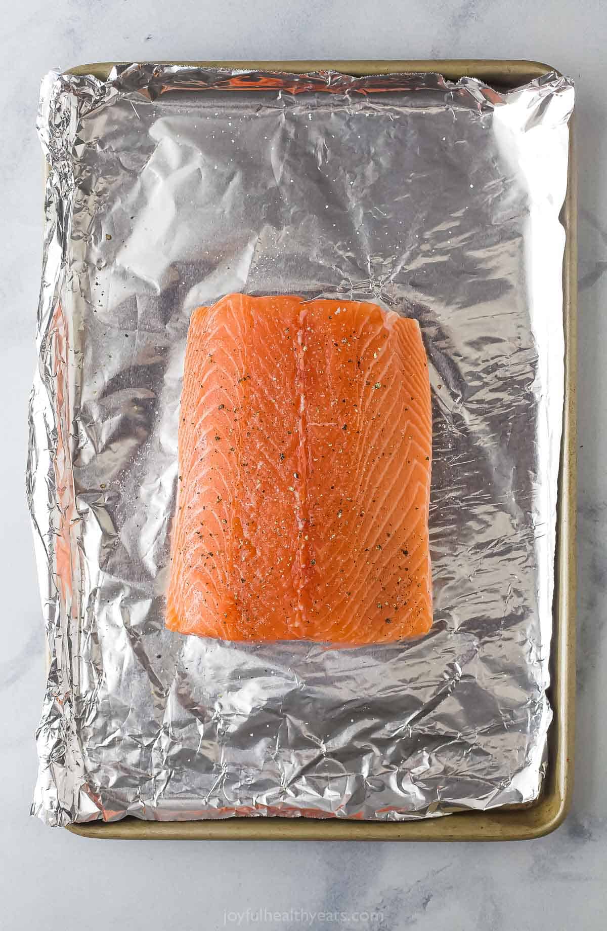 Fresh salmon fillet on a baking sheet.