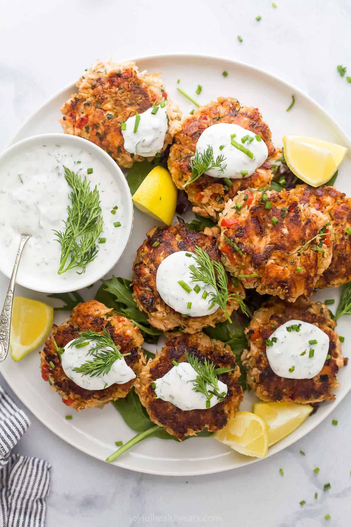 Plate of salmon patties with yogurt sauce on the side. 