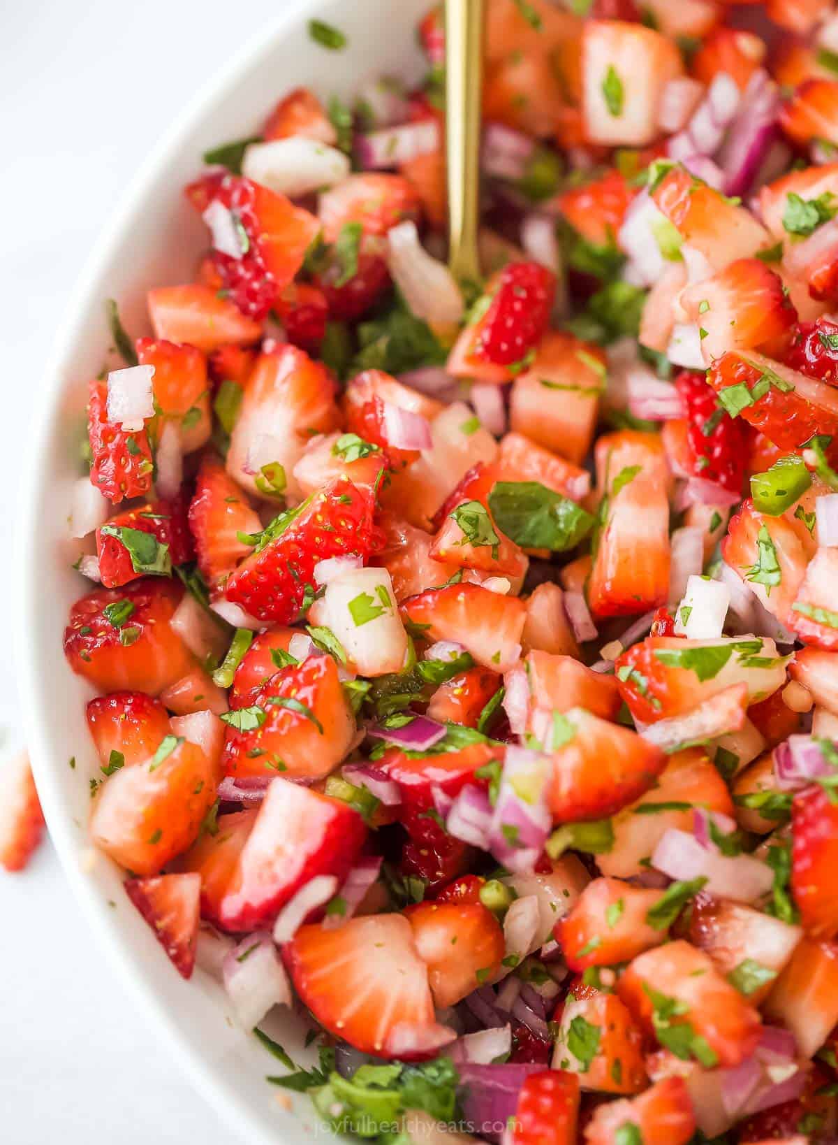 This 10-minute strawberry salsa is fruity, spicy, and tangy all in one bite. It's the perfect summer appetizer with corn chips! Close-up of fresh strawberry salsa.