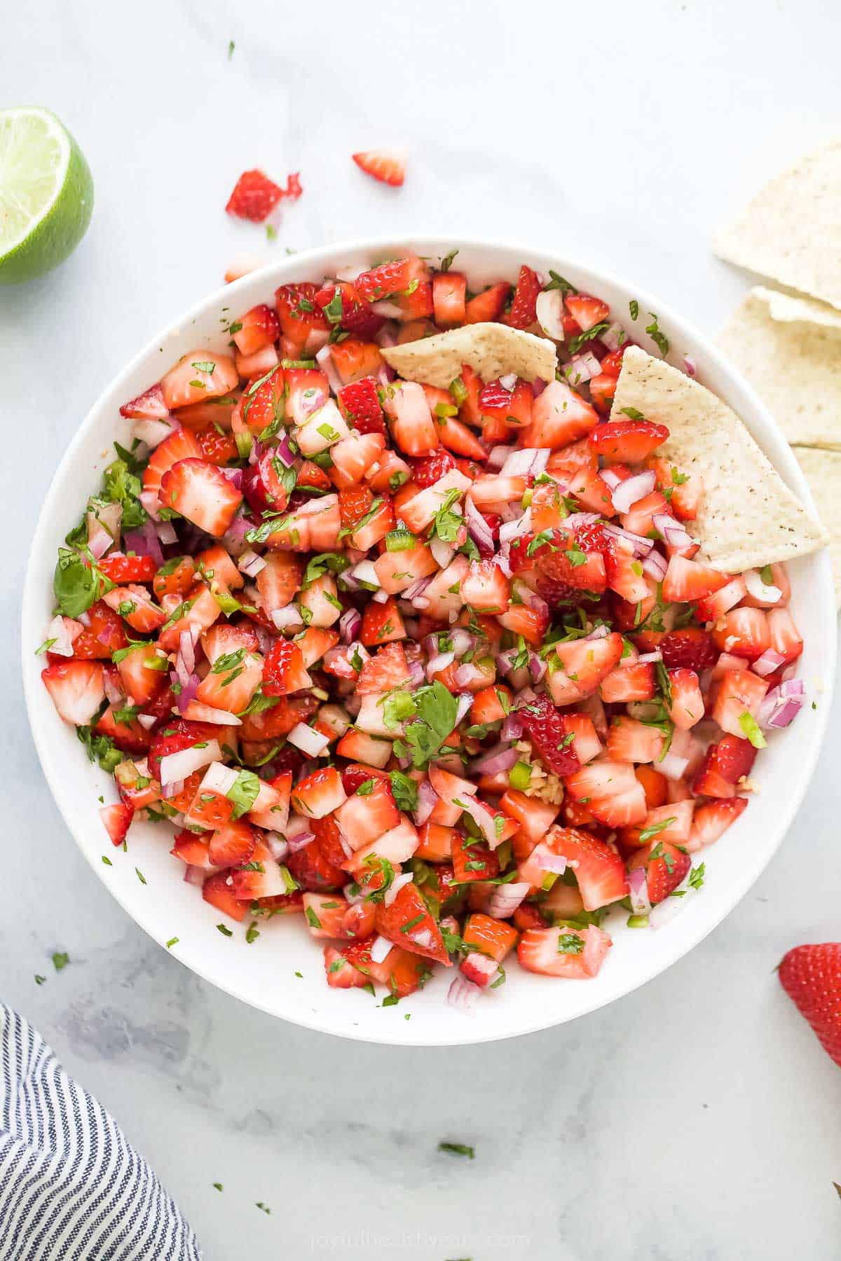 This 10-minute strawberry salsa is fruity, spicy, and tangy all in one bite. It's the perfect summer appetizer with corn chips! Bowl of strawberry jalapeno salsa.