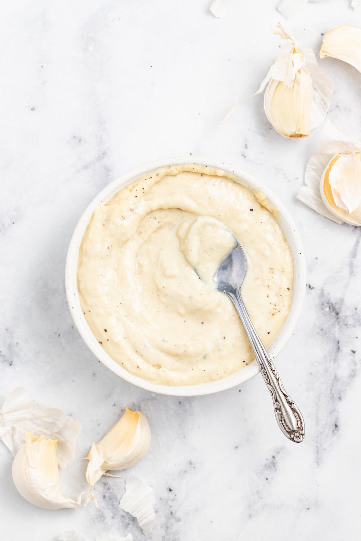 Bowl of aioli with a metal spoon inside. 