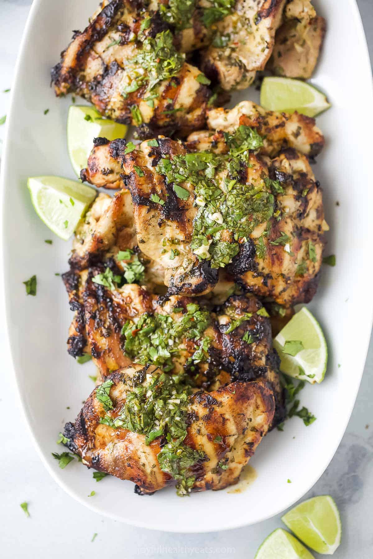 Topped with extra chimichurri, this juicy chimichurri chicken will be your new excuse to fire up the grill this summer. You'll love it! Close-up of chimichurri chicken topped with more chimichurri.