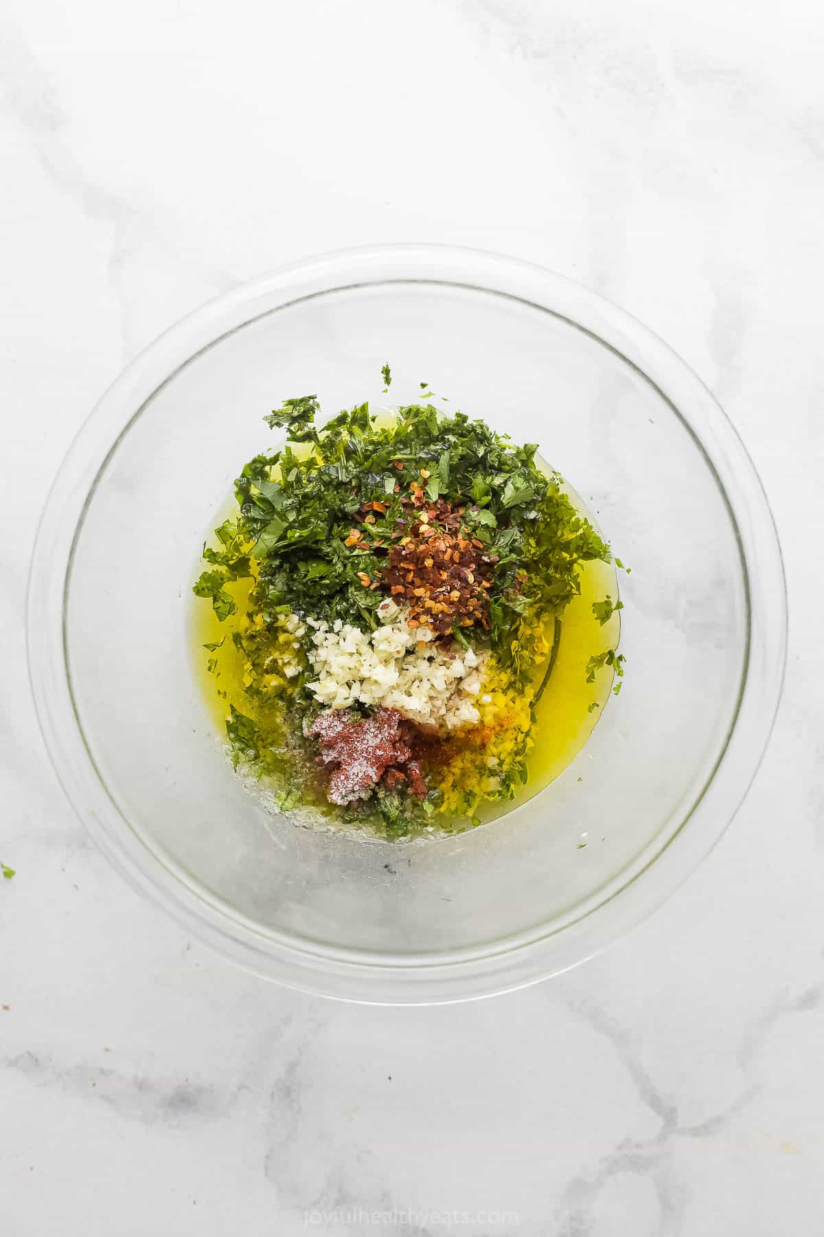 Adding the chimichurri ingredients to a bowl. 