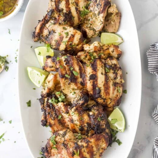Chimichurri chicken on a plate with lime wedges.