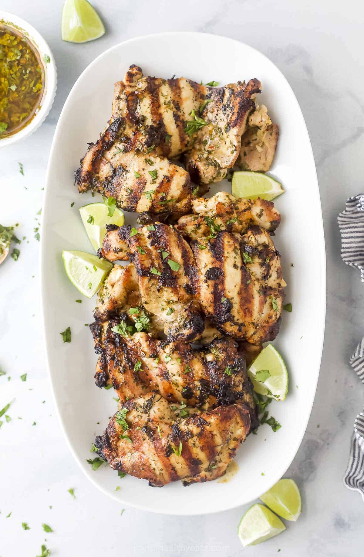 Chimichurri chicken on a plate with lime wedges. 