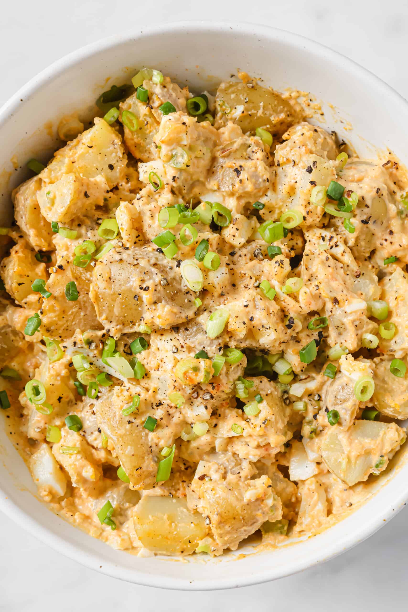 This easy deviled egg potato salad is creamy, tangy, and rich. Served chilled or warm, it'll be your new favorite summer side! Close-up of deviled egg potato salad.