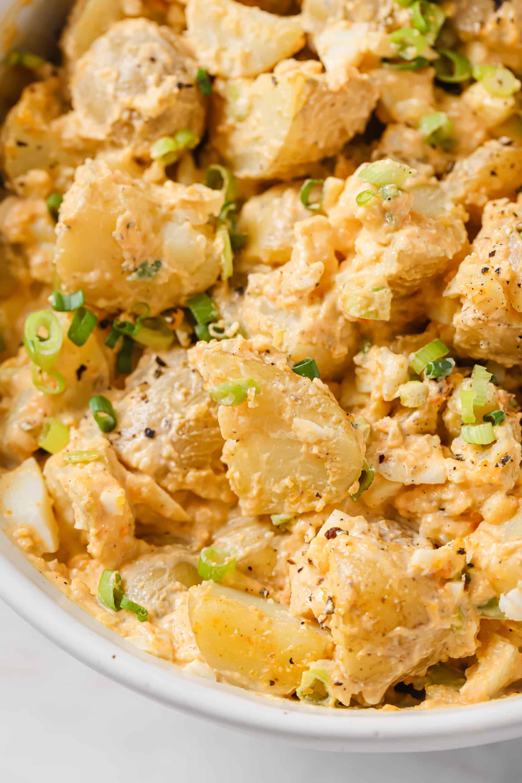 This easy deviled egg potato salad is creamy, tangy, and rich. Served chilled or warm, it'll be your new favorite summer side! Close-up of creamy potato salad.