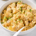 Bowl of deviled egg potato salad with green onions.