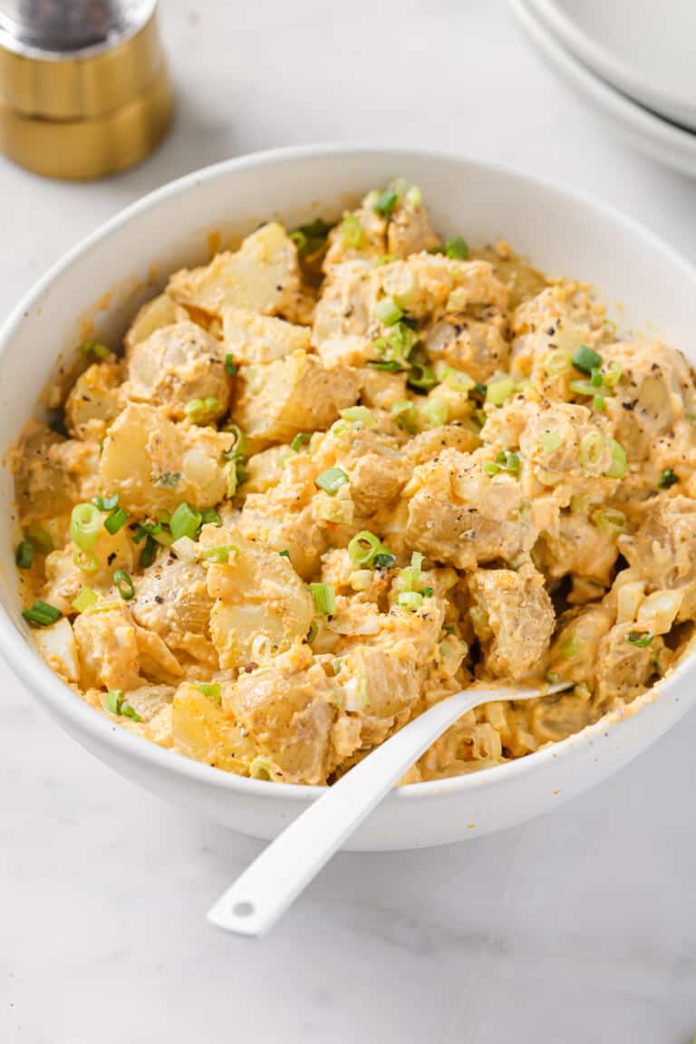 Bowl of deviled egg potato salad with green onions.