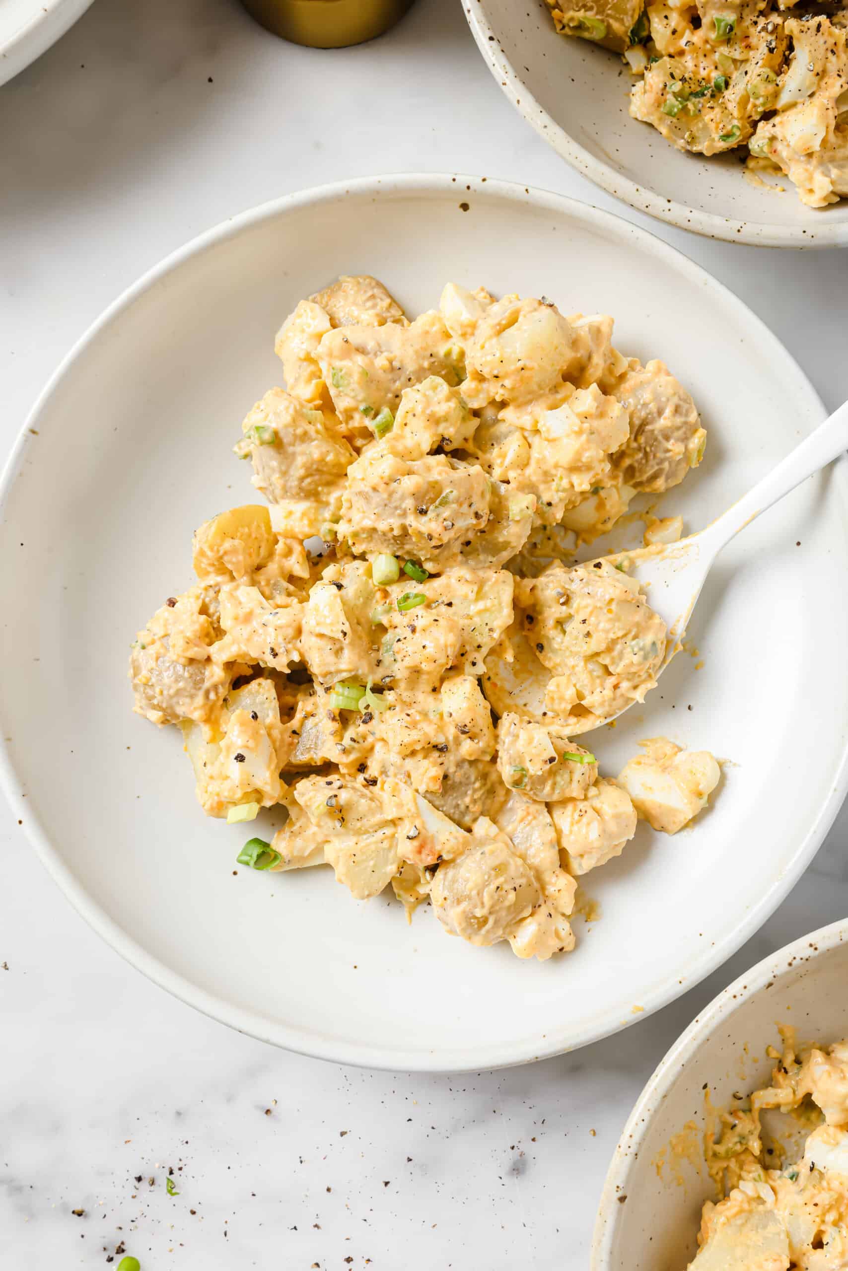 This easy deviled egg potato salad is creamy, tangy, and rich. Served chilled or warm, it'll be your new favorite summer side! Egg potato salad on a plate.