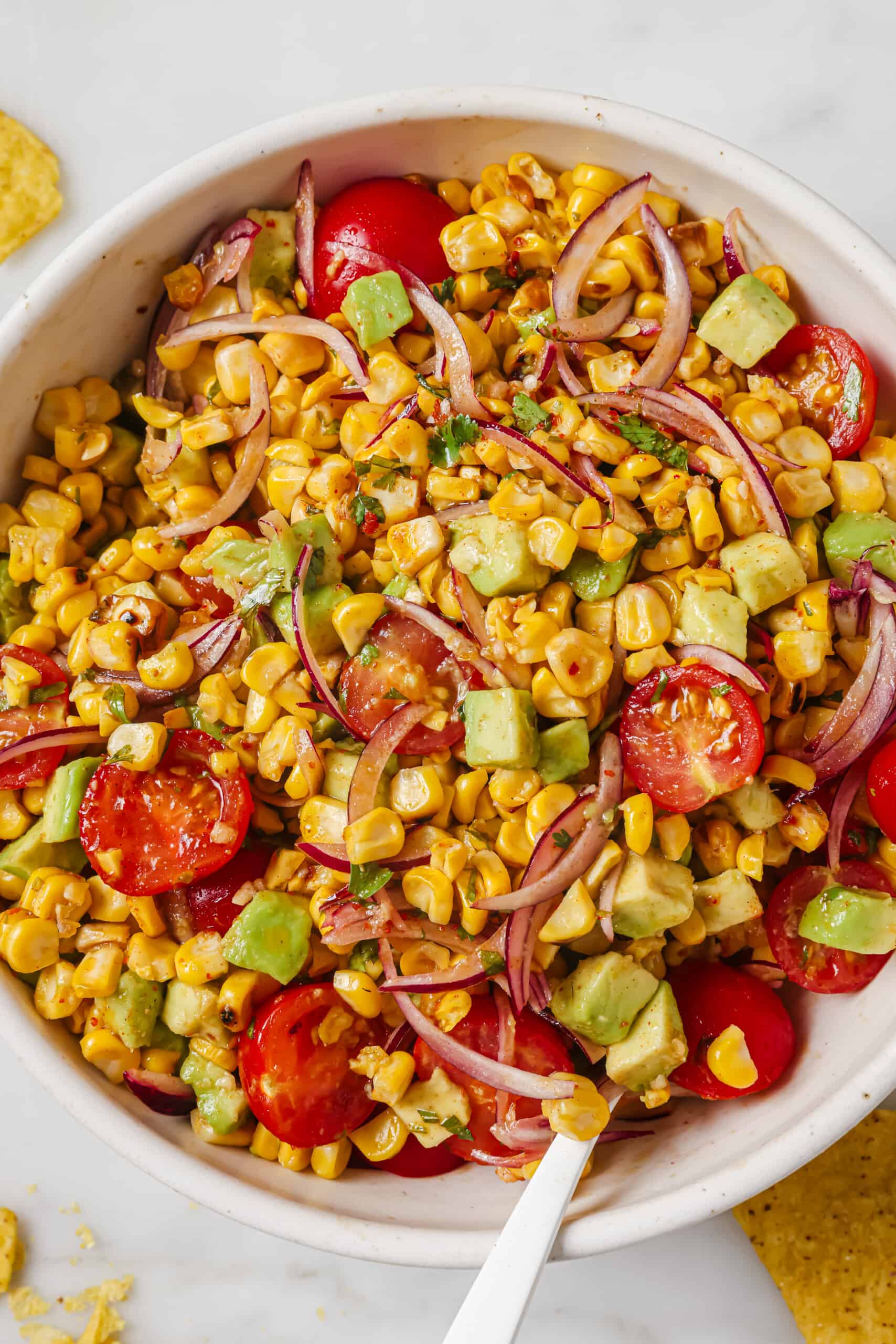 This easy avocado corn salad with a tangy honey dressing will find its way to your menu again and again. It's perfect! Close-up of avocado corn salad in a bowl.