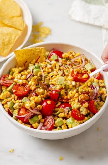 Bowl of avocado corn salad with corn chips.