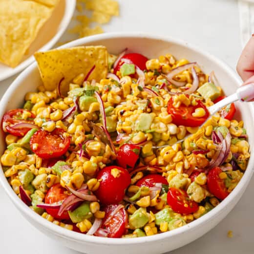 Bowl of avocado corn salad with corn chips.