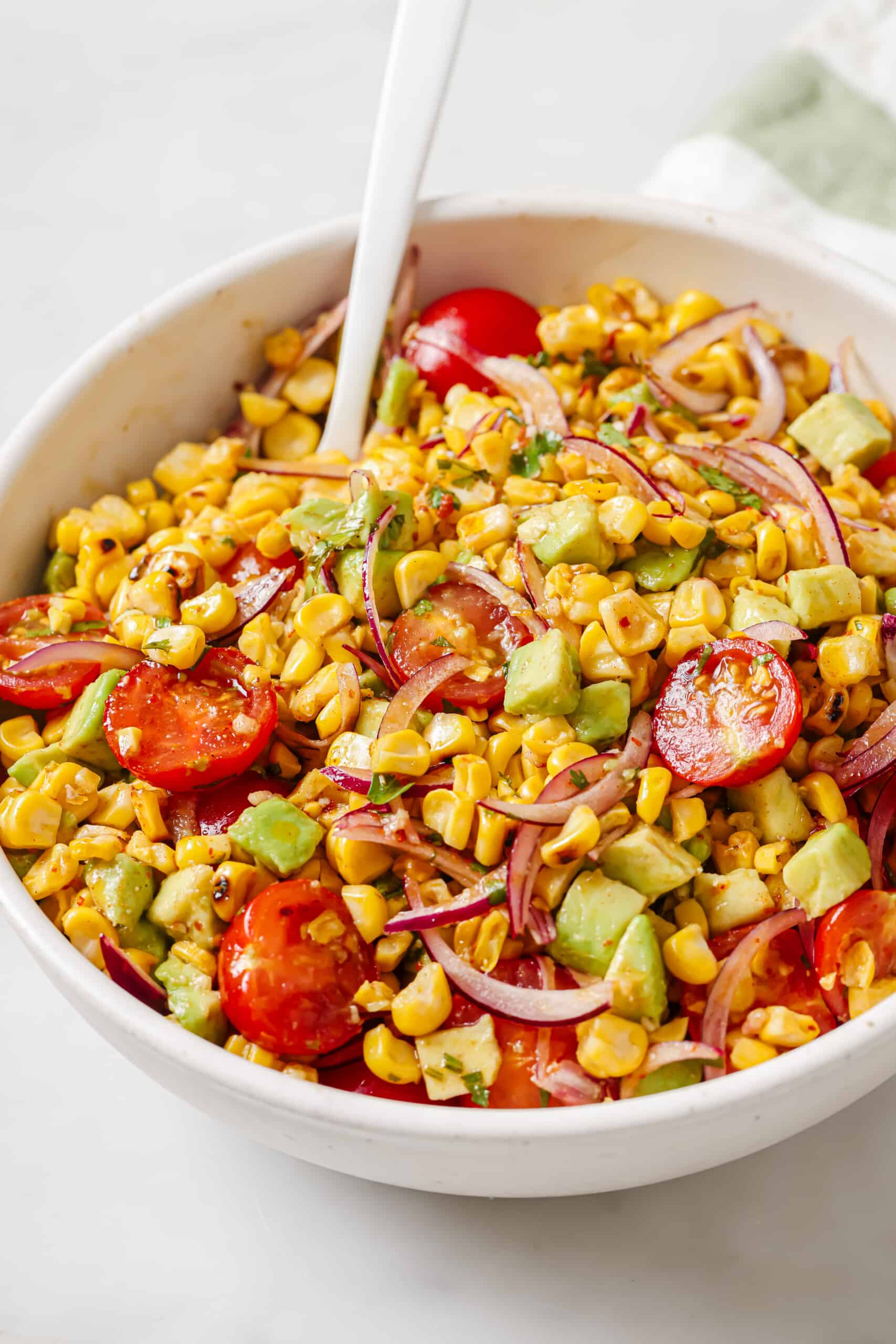 This easy avocado corn salad with a tangy honey dressing will find its way to your menu again and again. It's perfect! Bowl of grilled corn salad.