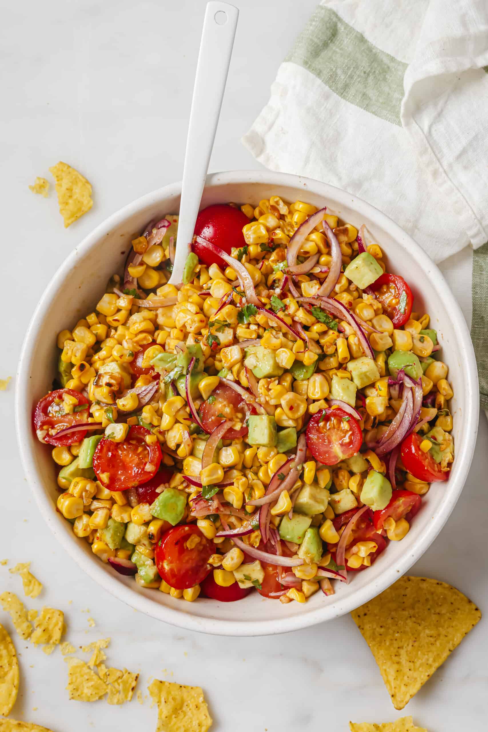 This easy avocado corn salad with a tangy honey dressing will find its way to your menu again and again. It's perfect! Overhead shot of corn avocado tomato salad.