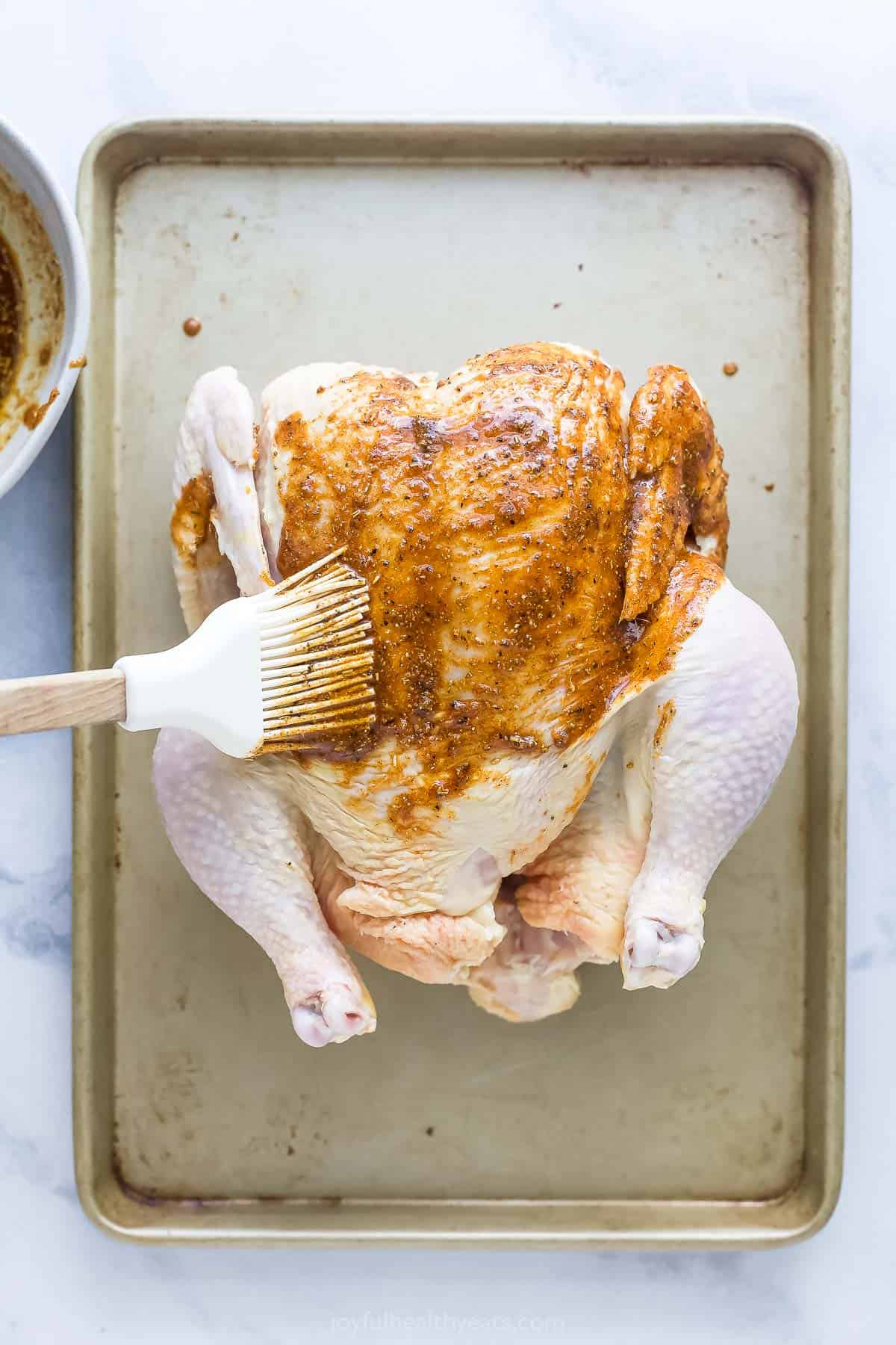 Brushing the spice rub on the chicken.