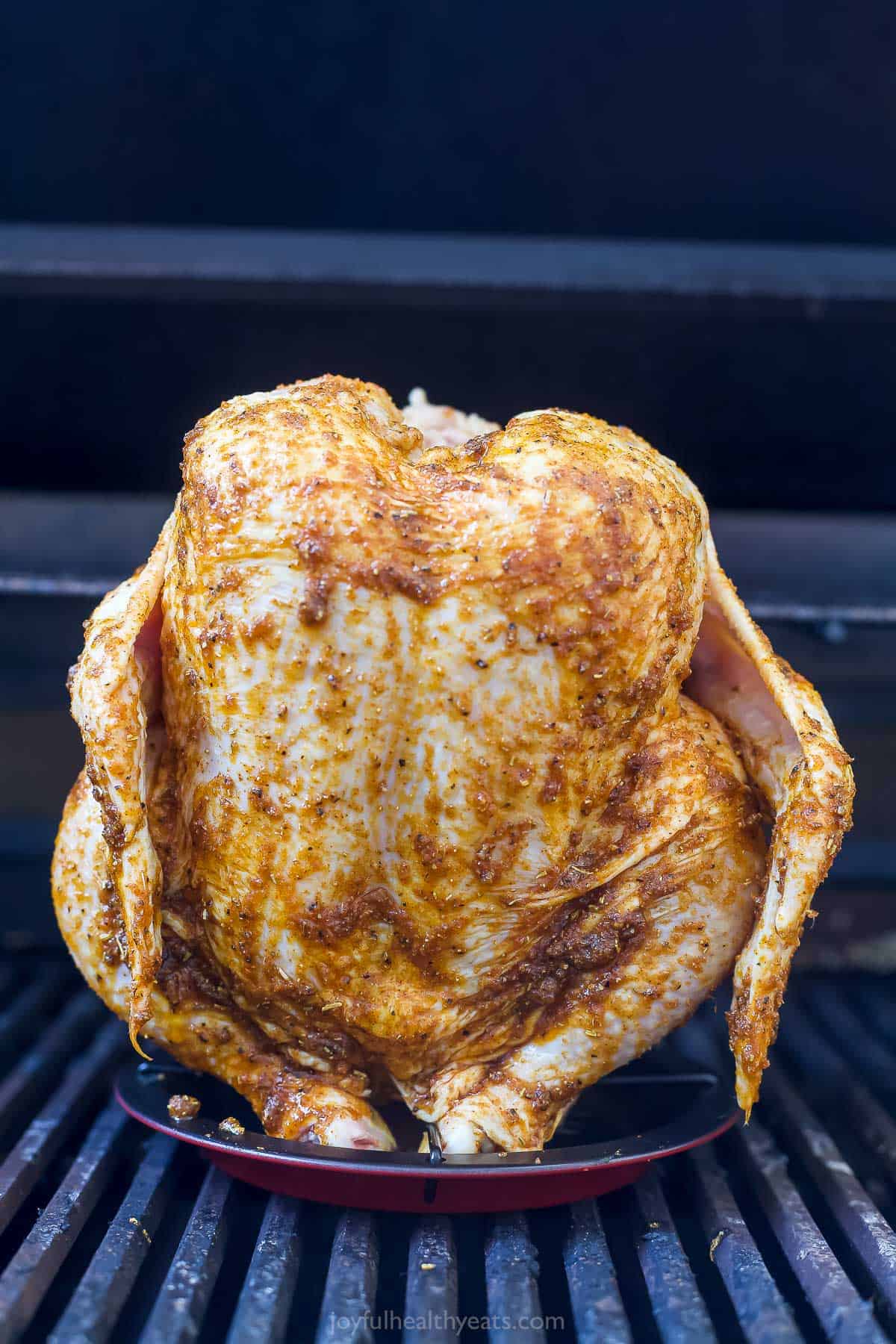 Placing the chicken on a vertical roaster.