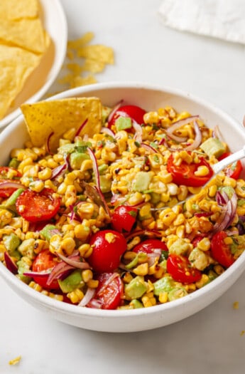 Bowl of avocado corn salad with corn chips.