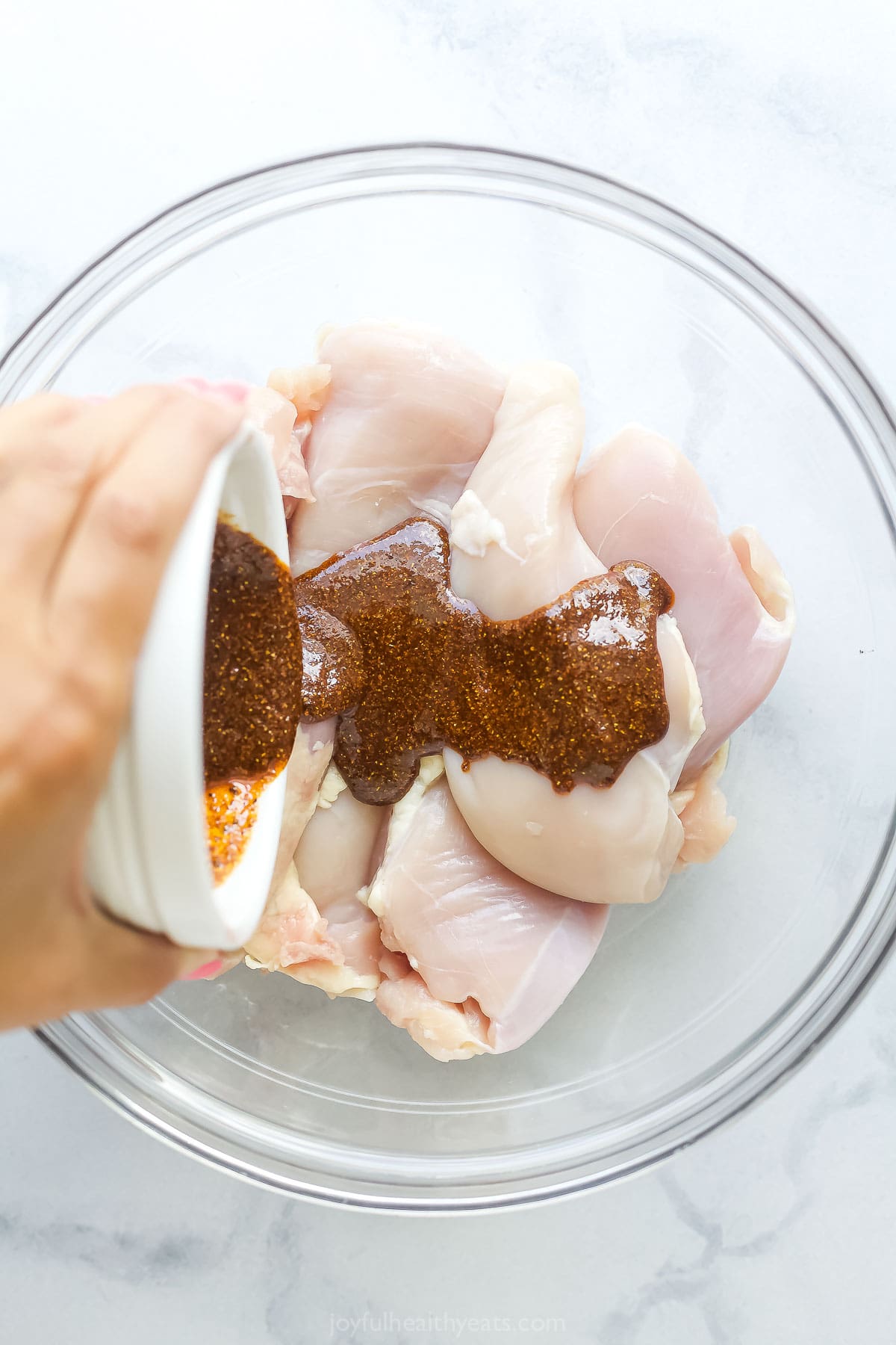 Pouring the spice mixture over the chicken. 