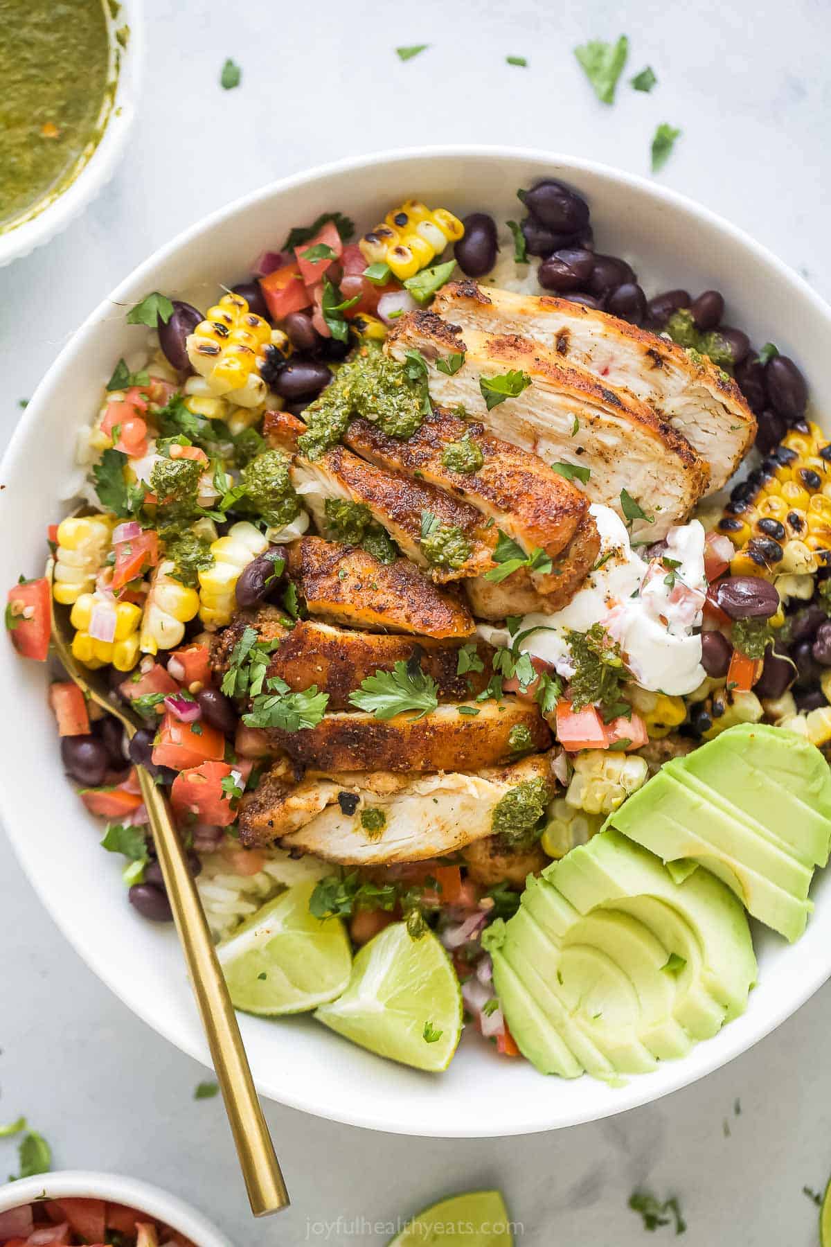 A chicken rice bowl with avocado and pico de gallo.