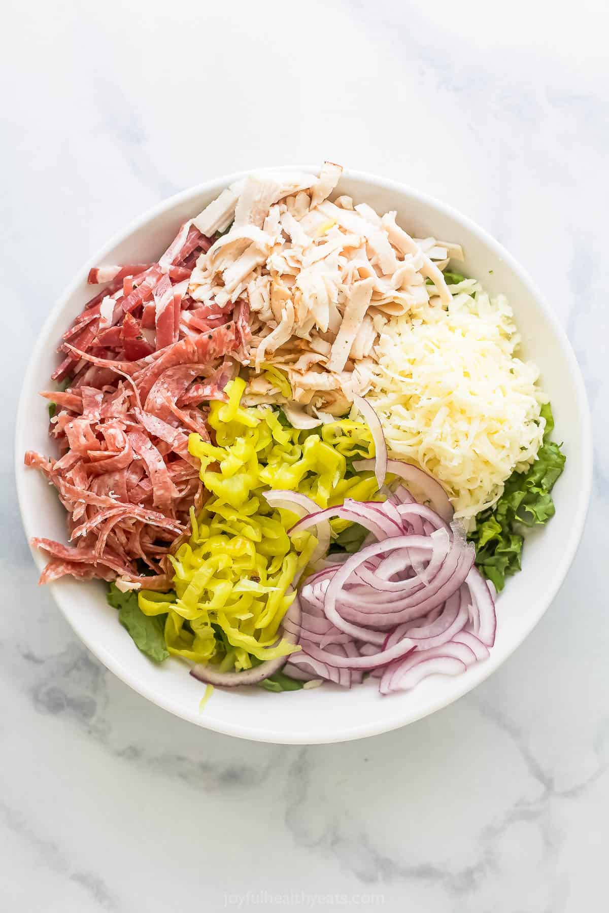 This easy Italian grinder salad recipe with homemade dressing is a trending 15-minute side that'll be a hit at the dinner table. Salad ingredients in a large bowl.