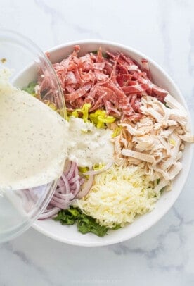 Adding the dressing to the salad ingredients. 