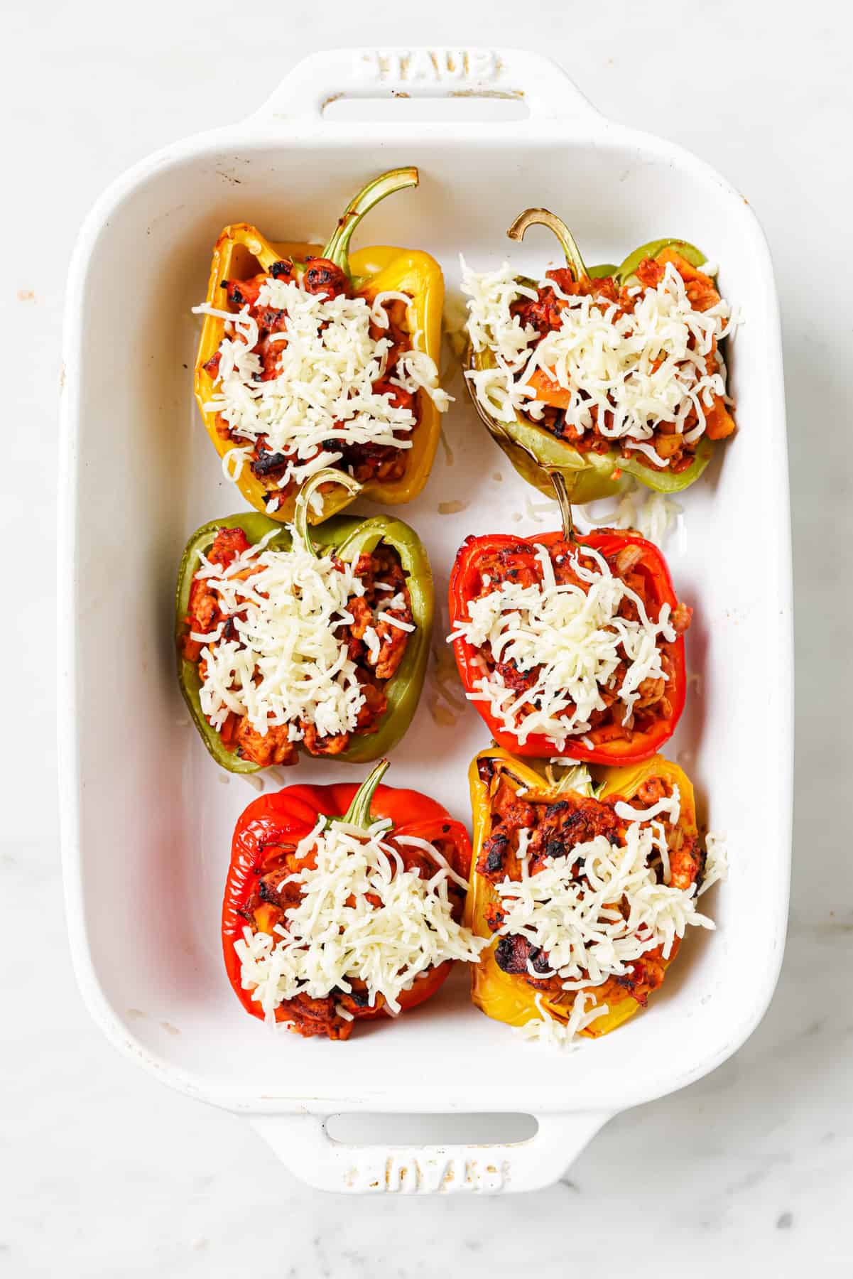 These Ground Turkey Stuffed Peppers are a simple dinner recipe filled with rich flavor your family will love. The perfect weeknight meal! Ground turkey stuffed peppers with cheese in dish before baking