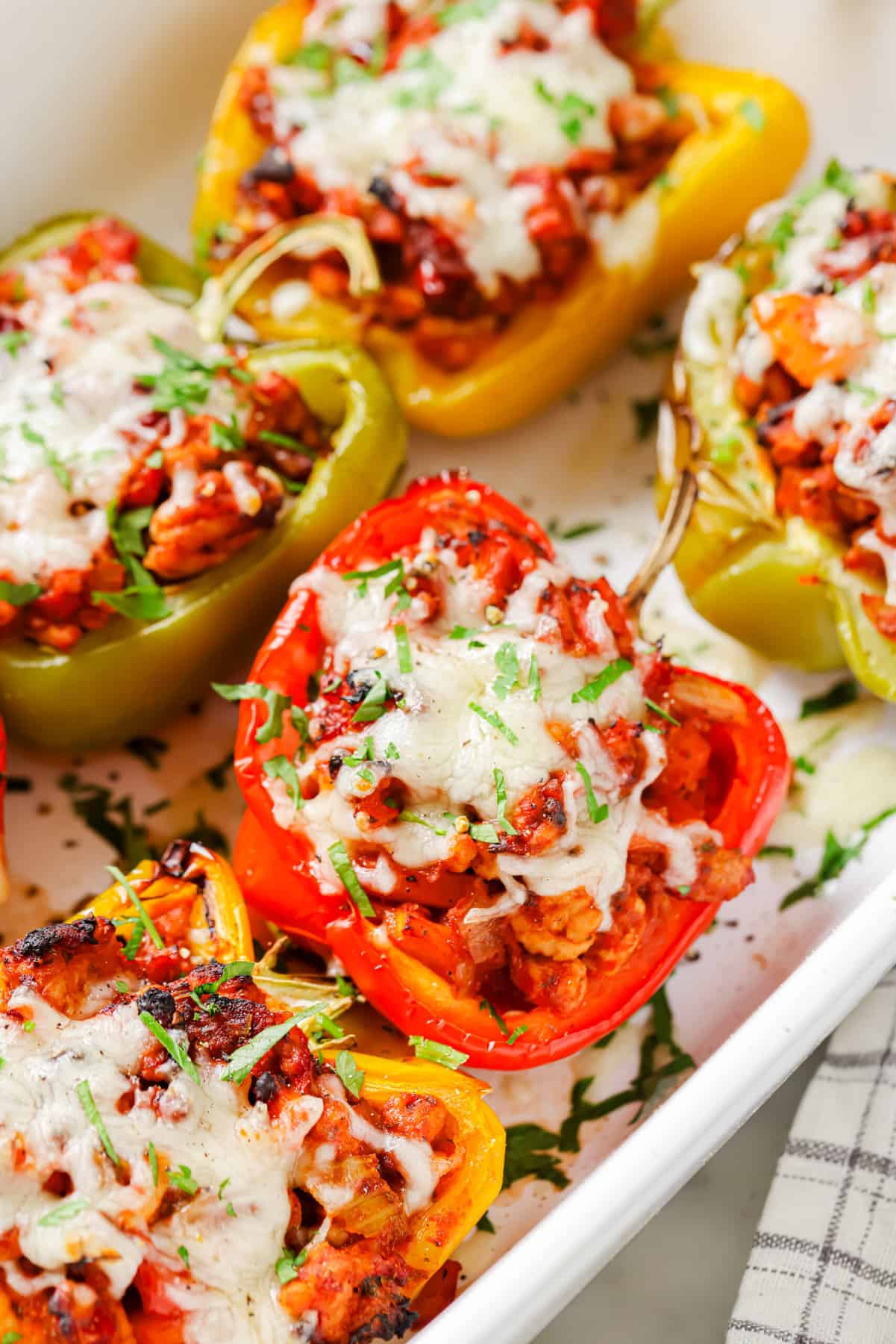 These Ground Turkey Stuffed Peppers are a simple dinner recipe filled with rich flavor your family will love. The perfect weeknight meal! Close-up of ground turkey stuffed peppers in the baking dish