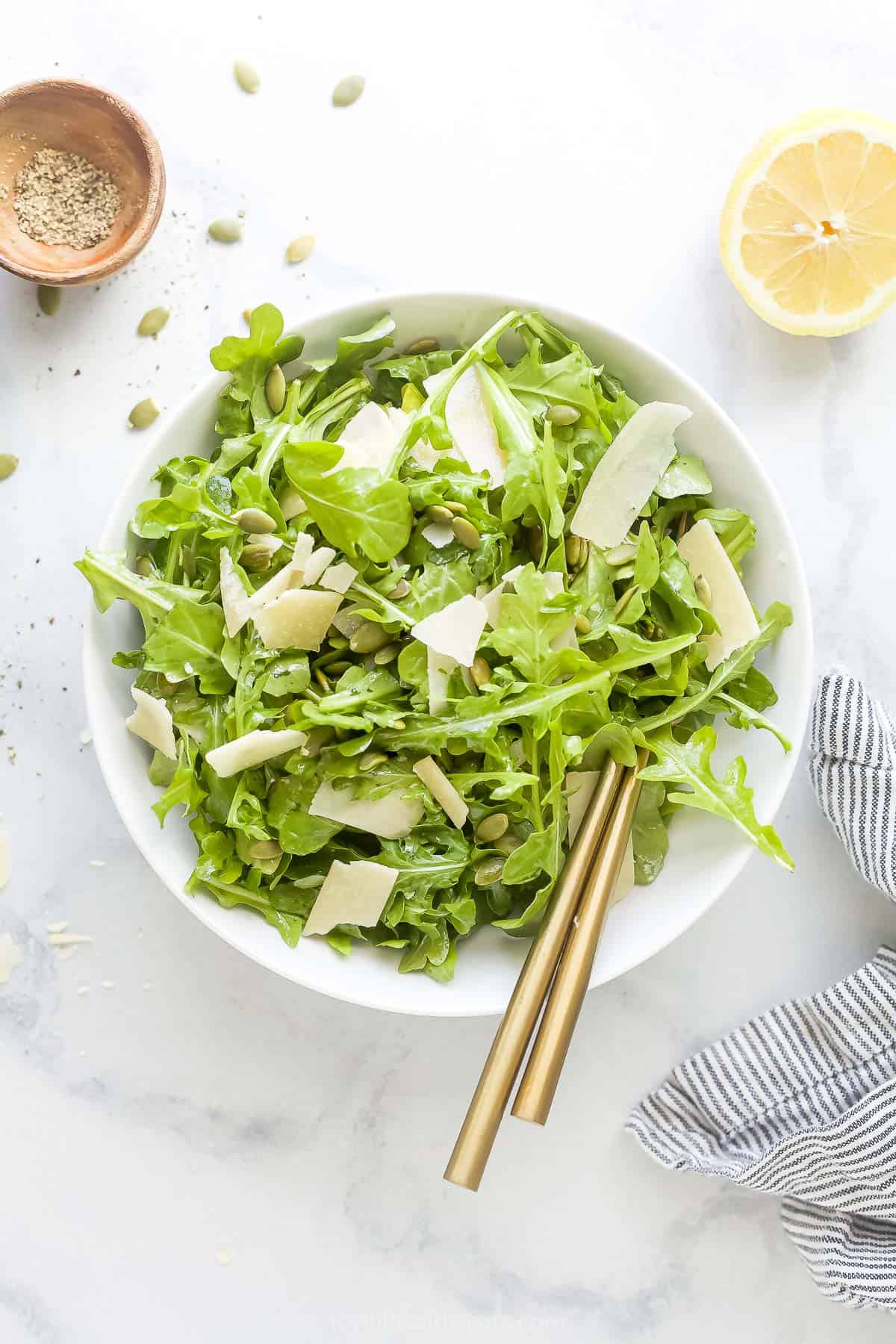 Bowl of arugula salad with shaved parmesan on top.