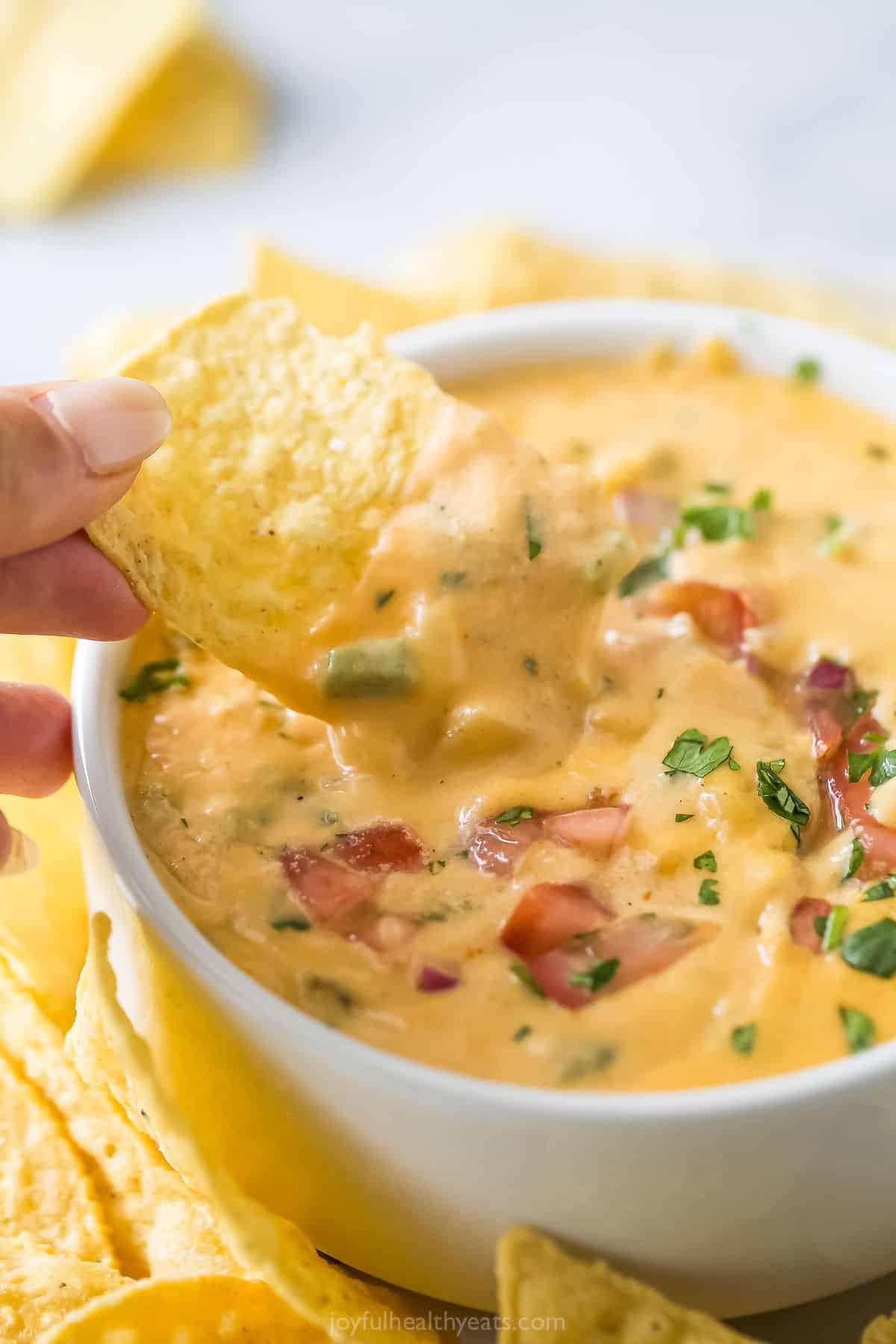 Dipping a corn chip into queso with pico de gallo. 