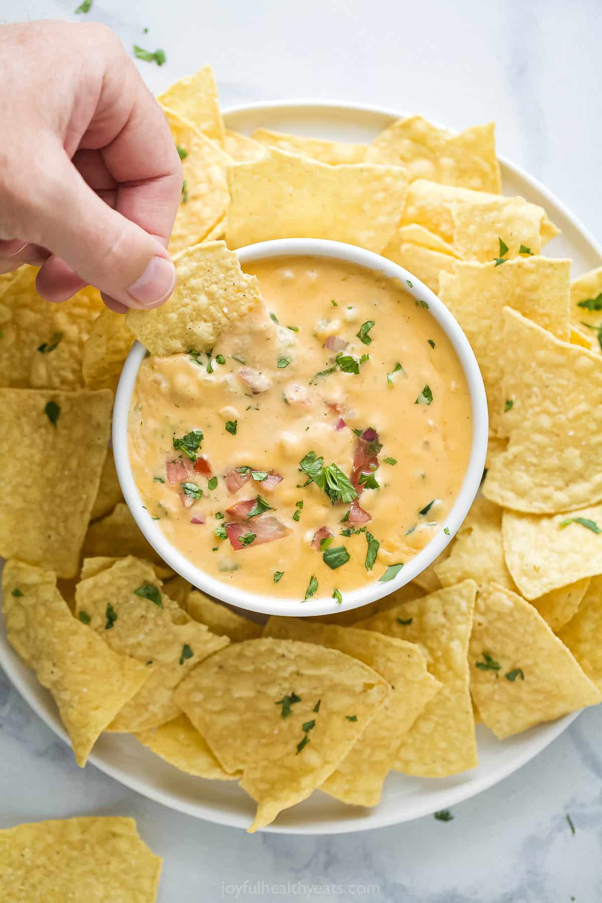 Dipping the corn chip into chile con queso. 