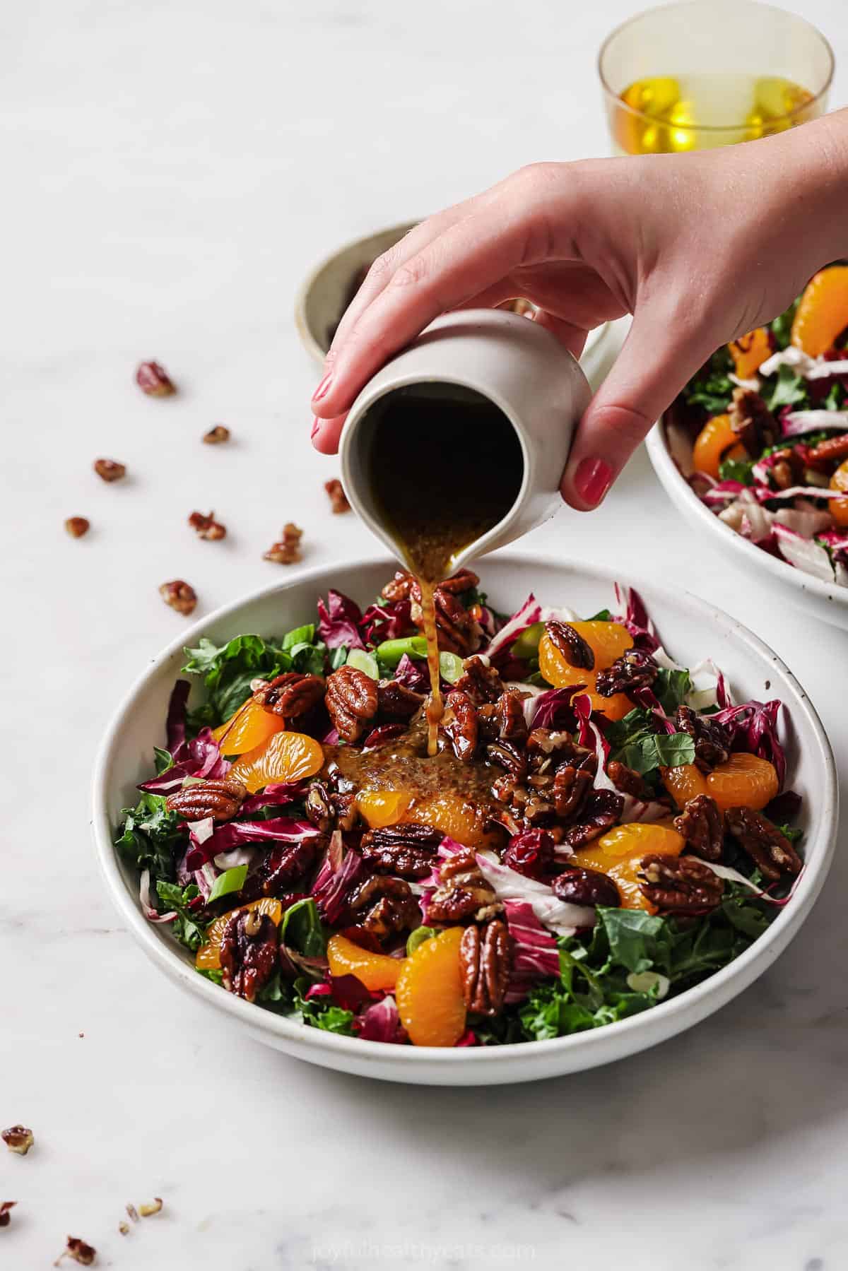 Drizzling the dressing over the salad.