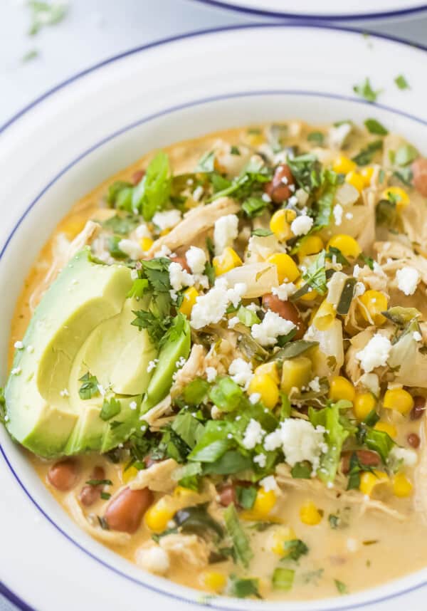 Close-up of creamy white chicken chili with avocado and cilantro.