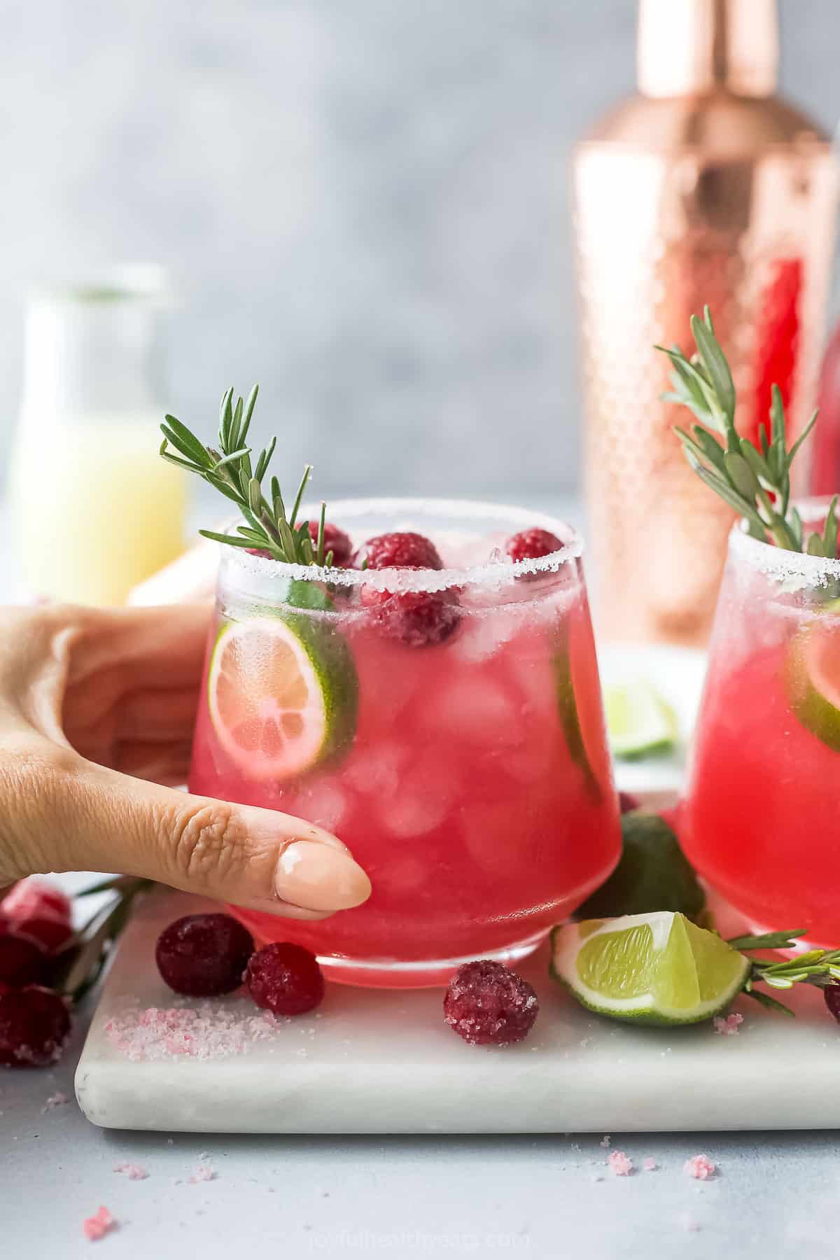 hand grabbing a mistletoe margarita in a glass