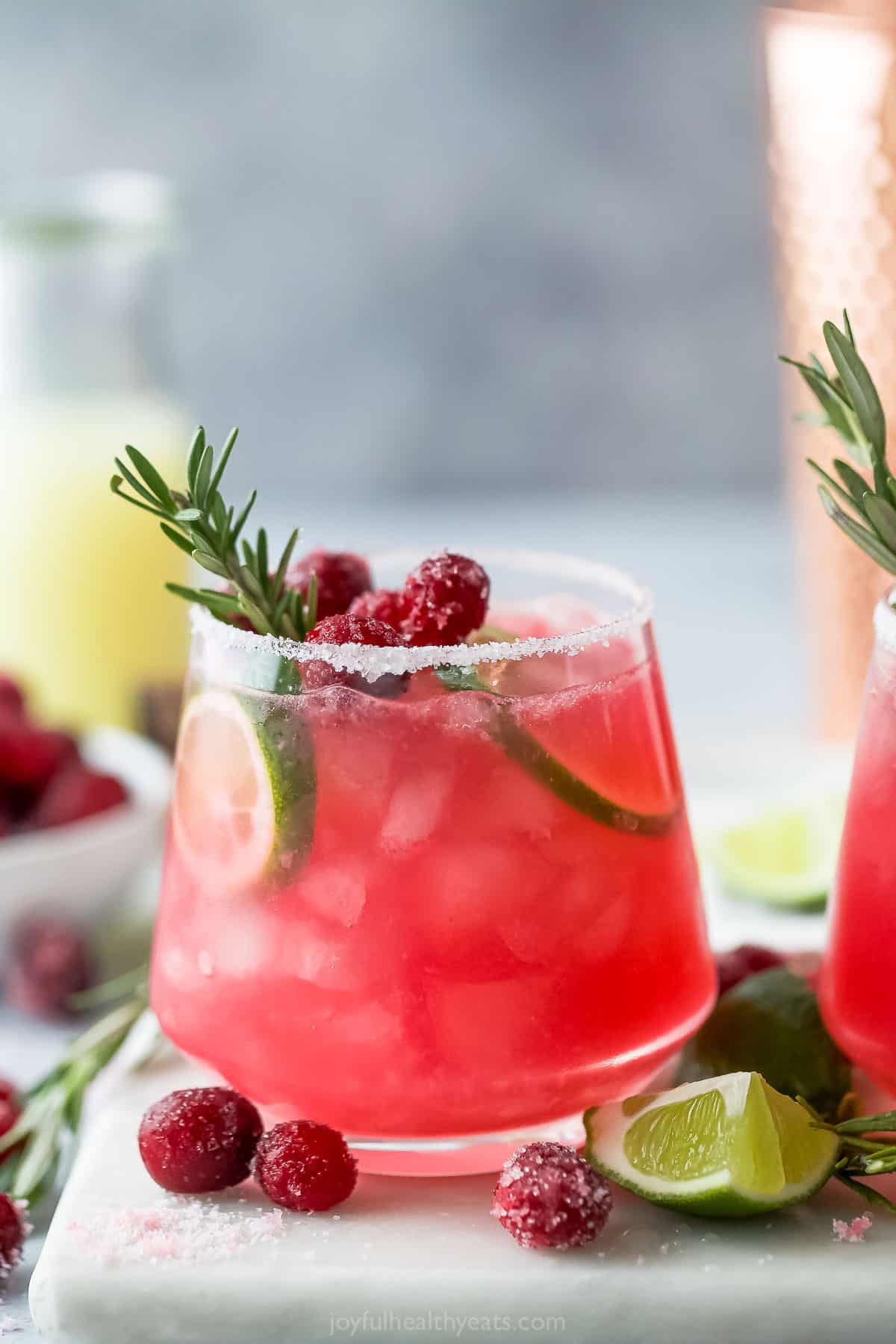 Close-up of mistletoe margarita garnished with cranberries, lime and rosemary