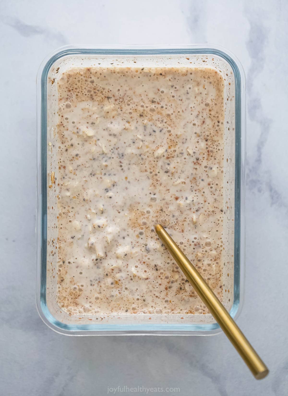 Mixed overnight oats mixture in a gl، container. 